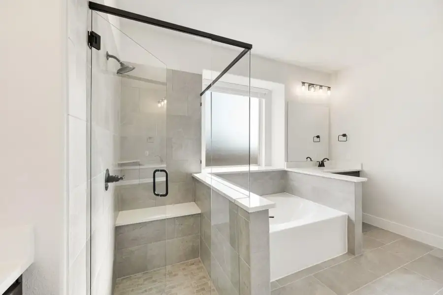 Master bathroom with glass walk-in shower, soaking tub, and gray tile throughout