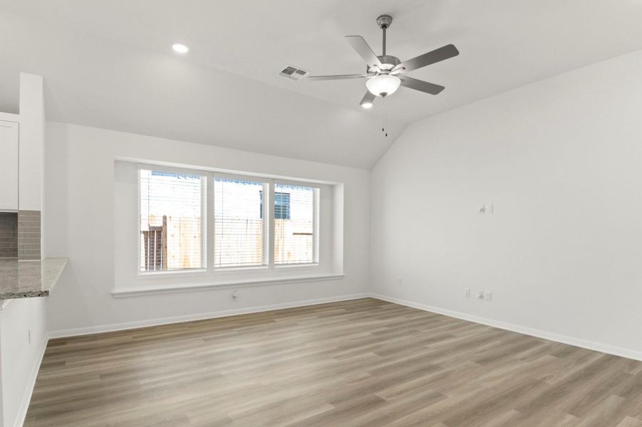 Unfurnished living room featuring light wood finished floors, vaulted ceiling, and ceiling fan