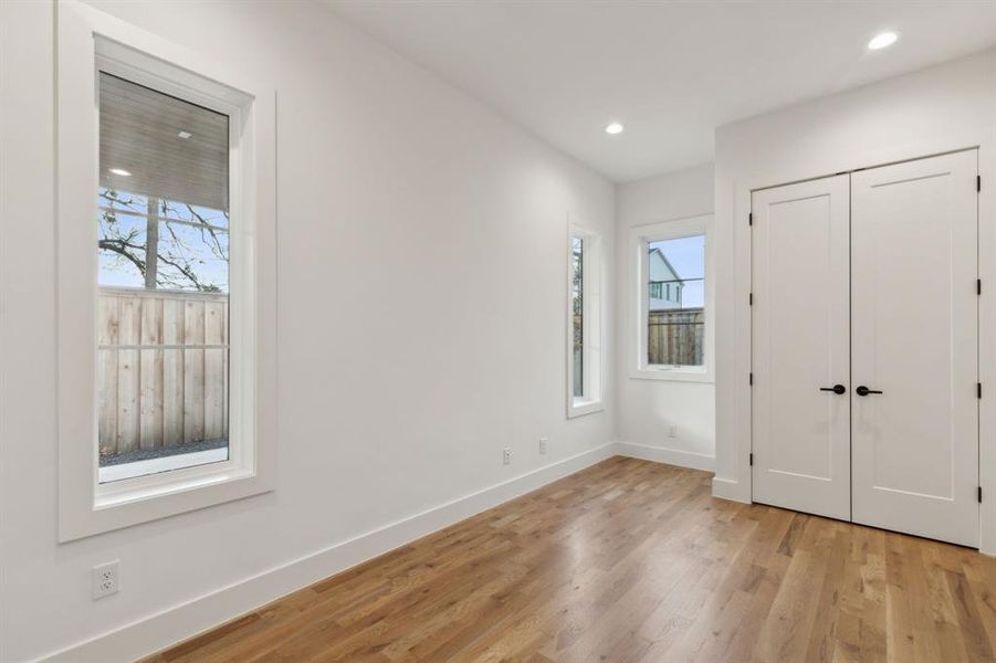 Unfurnished bedroom with a closet, multiple windows, and light hardwood / wood-style flooring