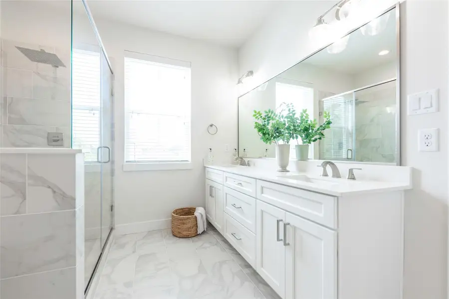 Luxurious primary bath featuring elegant marble finishes, a spacious glass-enclosed shower, and a double vanity with ample storage. Luxurious primary bath featuring elegant marble finishes, a spacious glass-enclosed shower, and a double vanity with ample storage.