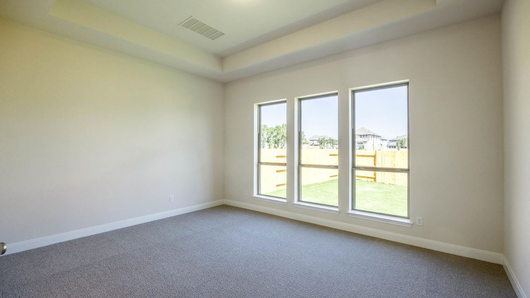 Carpeted empty room featuring a tray ceiling and baseboards Carpeted empty room featuring a tray ceiling and baseboards