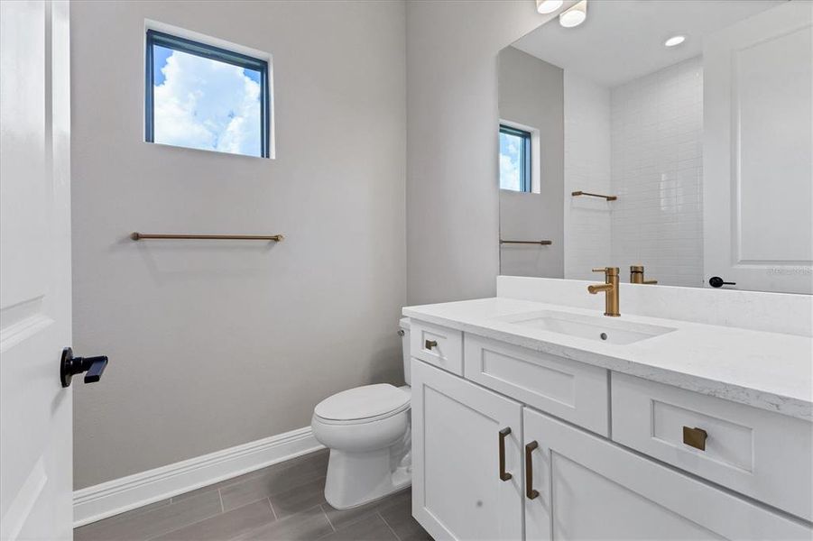 Main bath features brushed gold hardware and wood look tile floors.