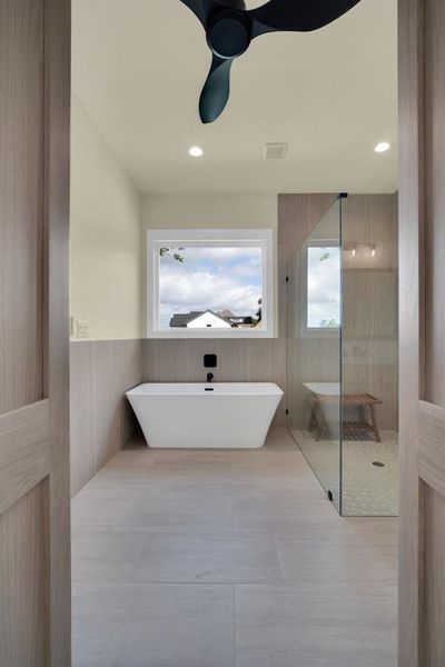 Bathroom with a washtub, ceiling fan, tile walls, and tile patterned flooring