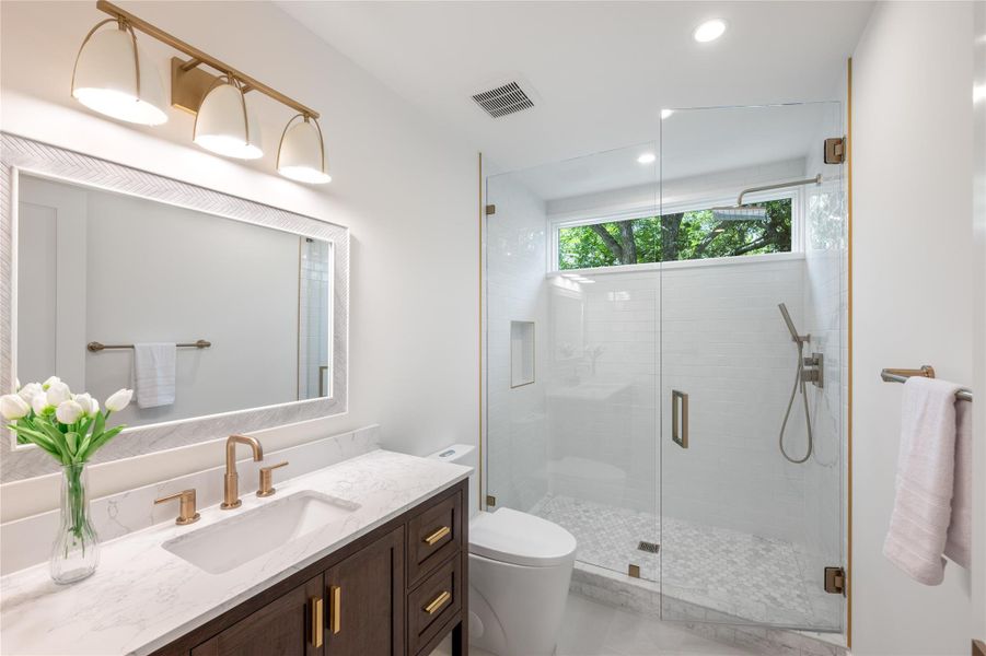 A well-lit bathroom features a modern vanity with a single sink and a glass-enclosed shower with subway tile. A well-lit bathroom features a modern vanity with a single sink and a glass-enclosed shower with subway tile.