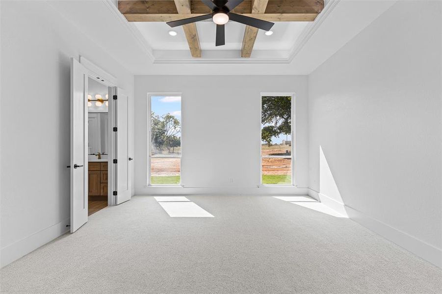 Unfurnished bedroom featuring beam ceiling, carpet, a ceiling fan, ensuite bath, and coffered ceiling