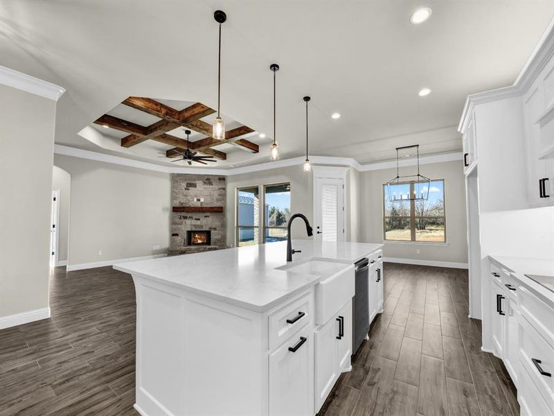 Kitchen with white cabinetry, beam ceiling, coffered ceiling, an island with sink, and stainless steel dishwasher