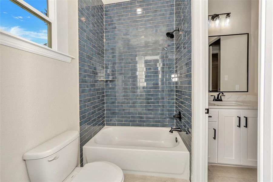 Full bathroom with toilet, tile patterned flooring, vanity, and tiled shower / bath