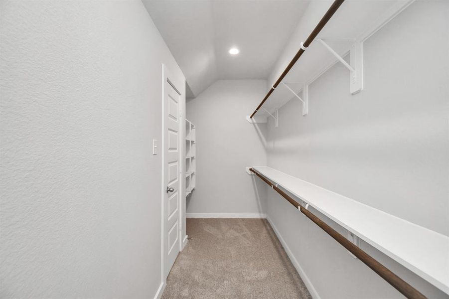 Walk-in closet that epitomizes luxury and practicality. This generously sized space features built-in shelving, offering abundant room for impeccable organization. High ceilings and recessed lighting create a bright and welcoming ambiance. Photo shown is example of completed home with similar plan. Actual colors and selections may vary.