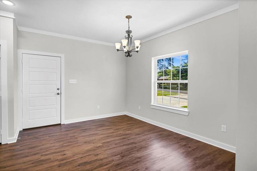 Spare room featuring a chandelier, ornamental molding, baseboards, and dark wood-style flooring