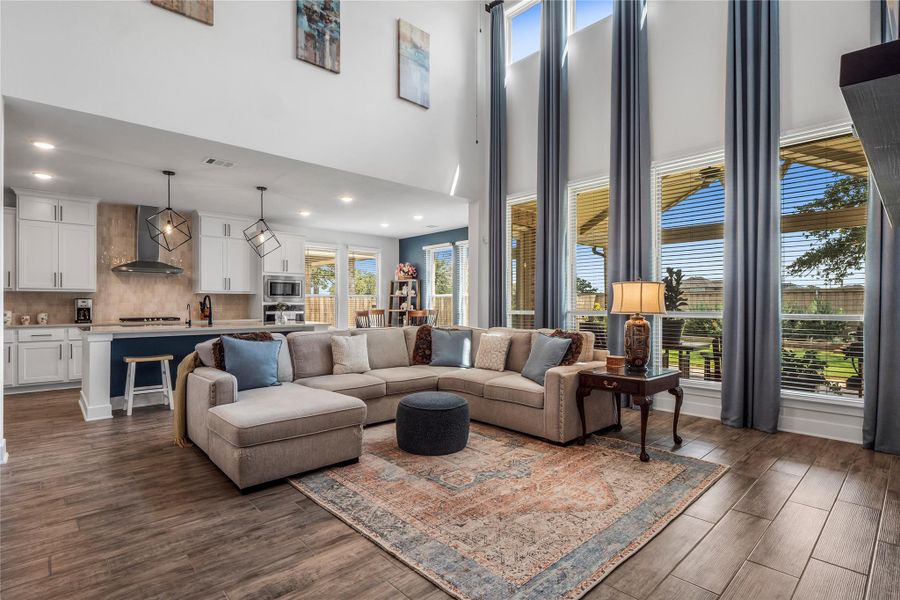 Living area with dark wood-type flooring, a high ceiling, and recessed lighting Living area with dark wood-type flooring, a high ceiling, and recessed lighting
