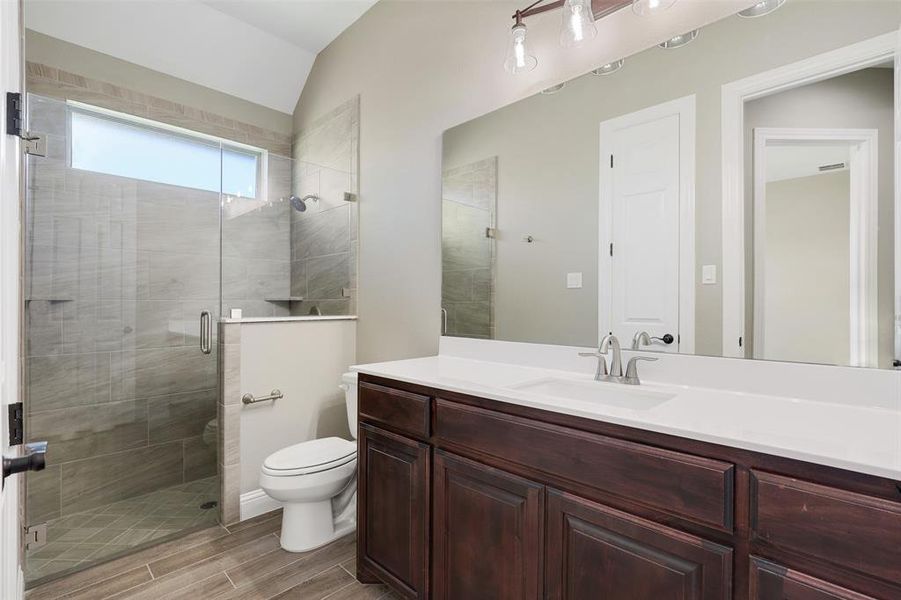 Bathroom with vaulted ceiling, vanity, an enclosed shower, and toilet