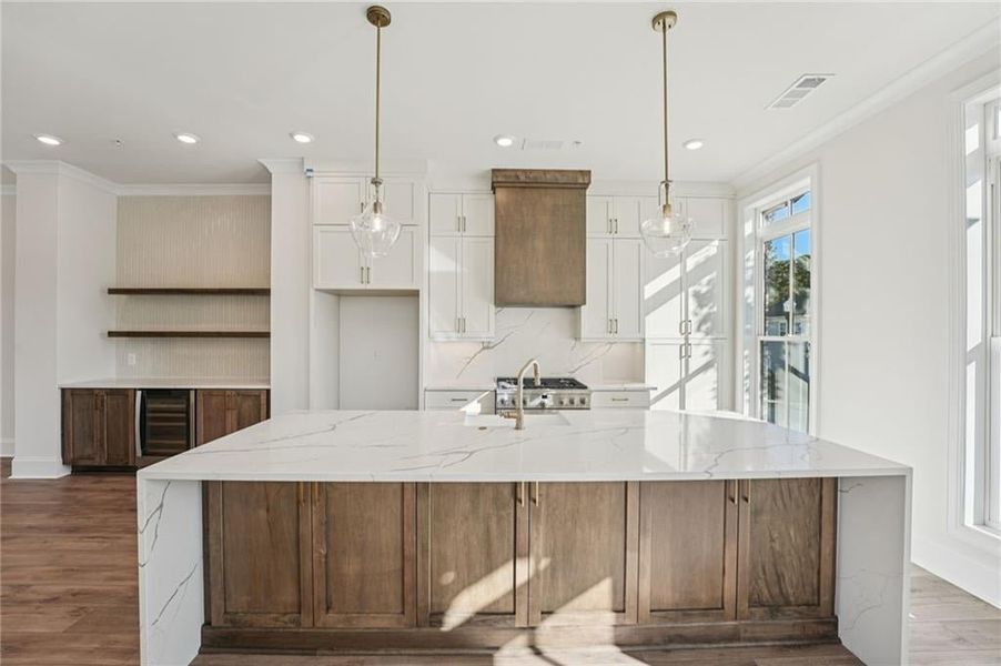 Kitchen featuring light stone countertops, crown molding, tasteful backsplash, light wood-type flooring, and open shelves Kitchen featuring light stone countertops, crown molding, tasteful backsplash, light wood-type flooring, and open shelves