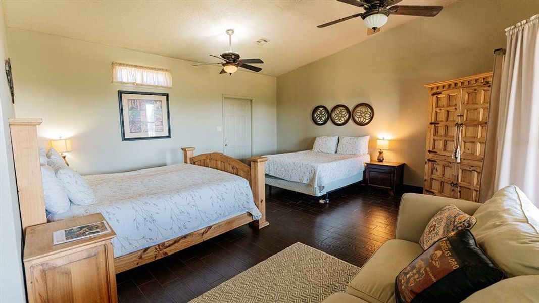 Bedroom featuring vaulted ceiling, dark wood finished floors, and a ceiling fan
