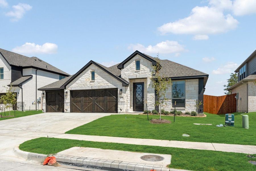 Single-story home with light stone exterior, two-car garage with wood doors, and green front lawn.