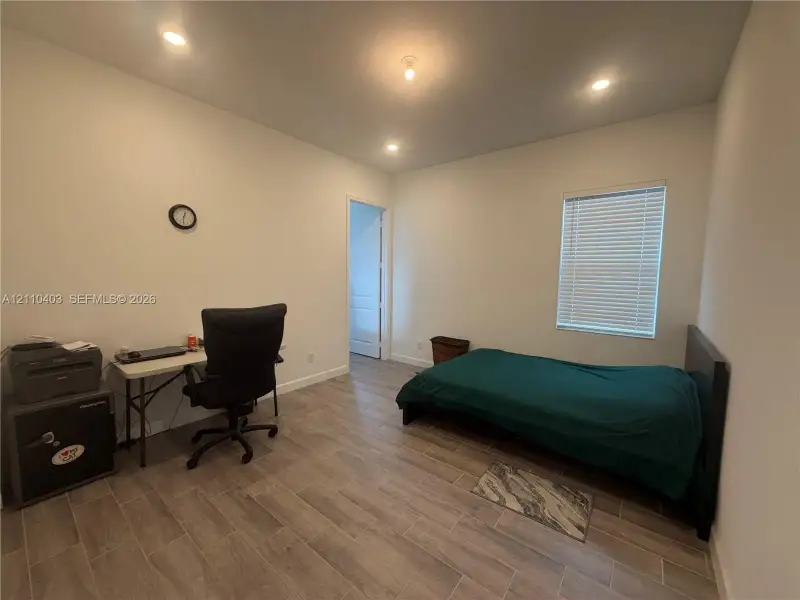 Room with wood-finish flooring, recessed lighting, and a window with integrated blinds