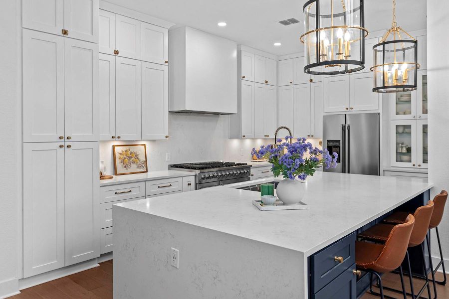 Kitchen with hanging light fixtures, high end appliances, a large island, and white cabinets