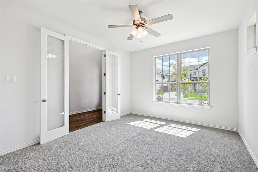 Unfurnished bedroom featuring carpet floors, french doors, and ceiling fan