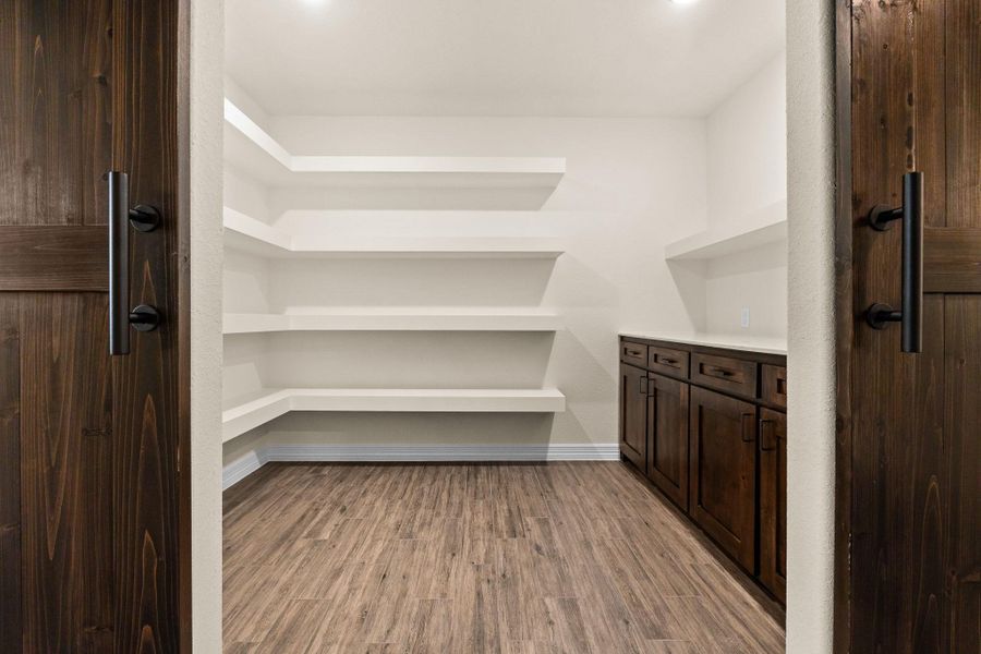 View of pantry, built-in shelves, dark brown cabinets, and granite countertops. View of pantry, built-in shelves, dark brown cabinets, and granite countertops.