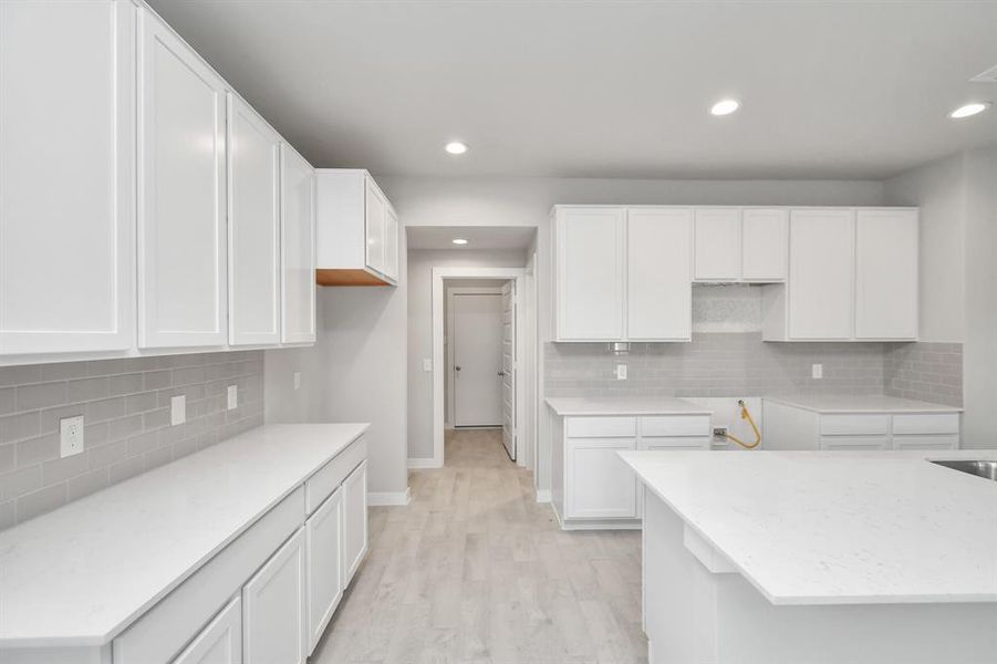 Discover another perspective of this stunning kitchen, generously appointed with an abundance of counter space. Sample photo of completed home with similar floor plan. As-built interior colors and selections may vary.