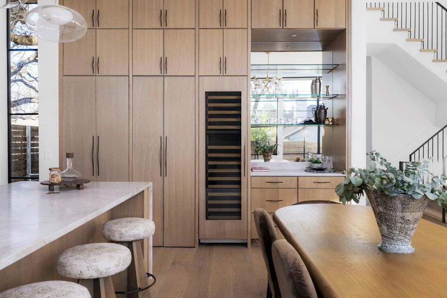 Indoor wet bar featuring beverage cooler, light stone countertops, light wood-type flooring, modern cabinets, and plenty of natural light