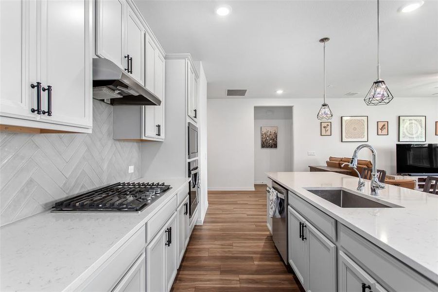 Kitchen with under cabinet range hood, stainless steel appliances, decorative backsplash, recessed lighting, and dark wood-style flooring
