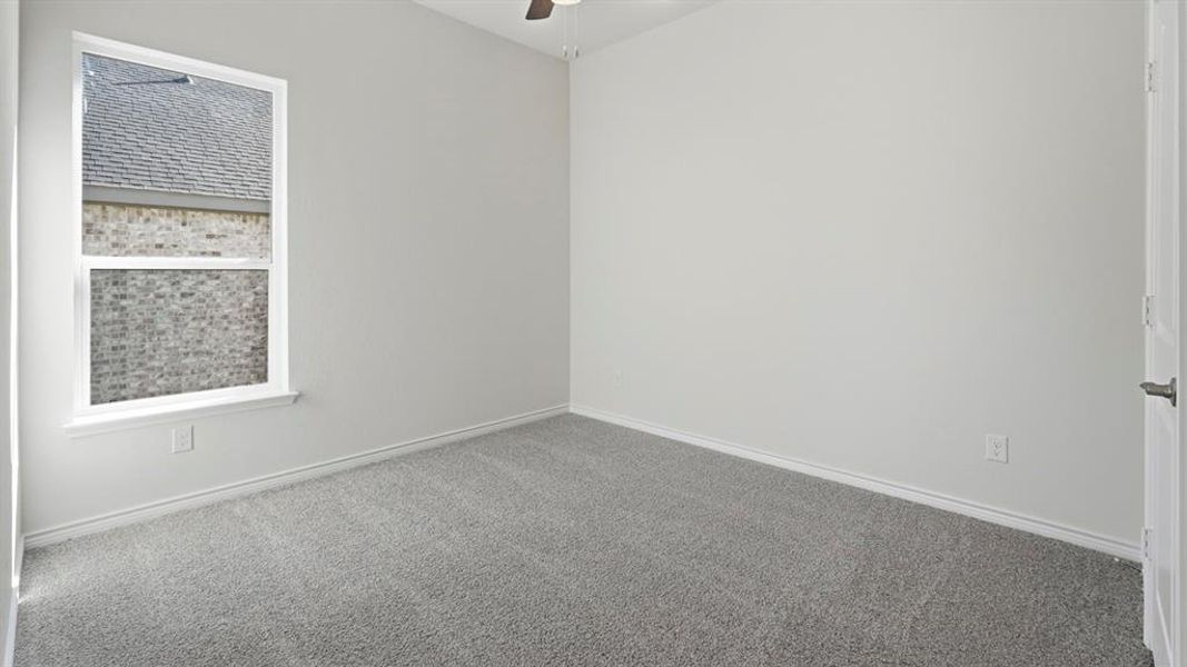 The room features light gray carpeting, white walls, and a window with a white frame The room features light gray carpeting, white walls, and a window with a white frame