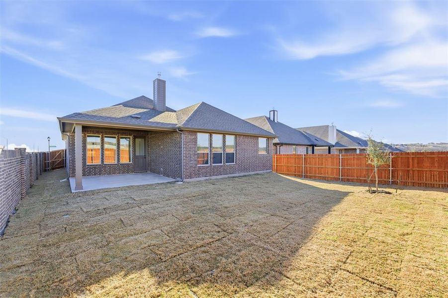 Rear view of property featuring a fenced backyard, a chimney, a patio, roof with shingles, and brick siding