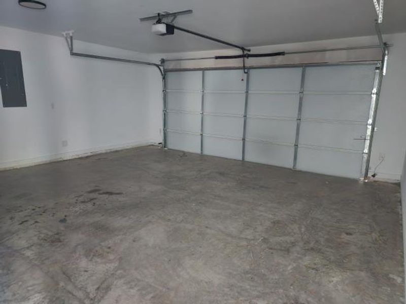 Garage featuring electric panel and baseboards Garage featuring electric panel and baseboards