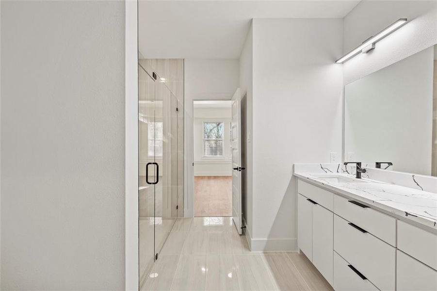 Full bathroom with a stall shower, vanity, and baseboards