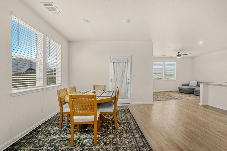 Natural light floods this inviting dining area with practical wood flooring leading into an open living space.