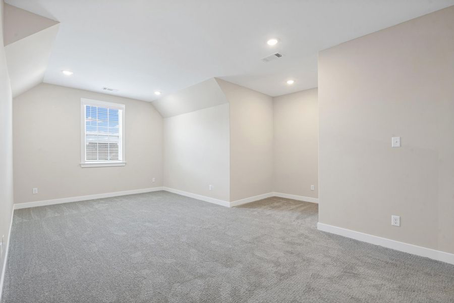 Versatile loft space featuring sloped ceilings, recessed lighting, and soft grey carpeting Versatile loft space featuring sloped ceilings, recessed lighting, and soft grey carpeting