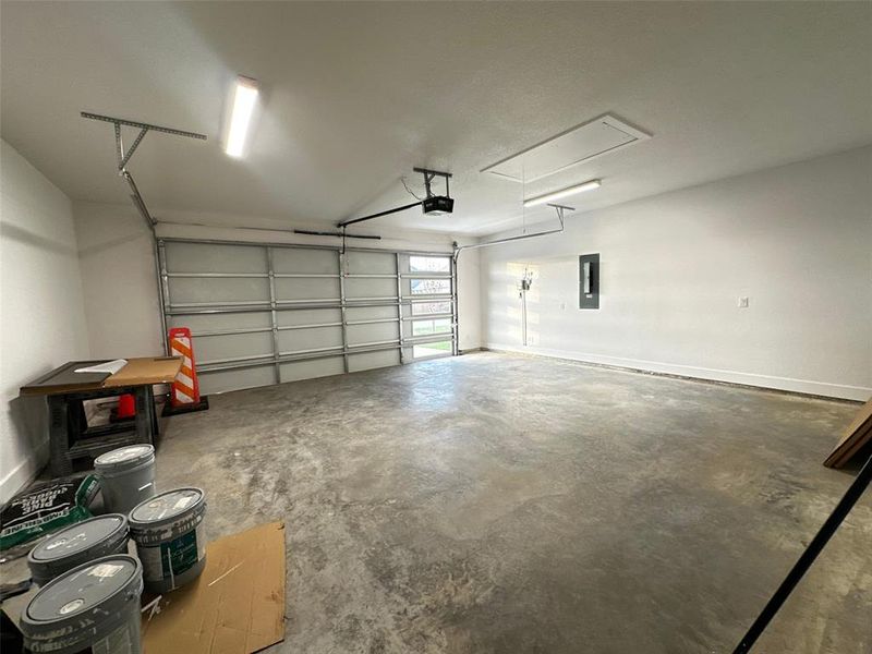 Garage featuring a garage door opener and electric panel