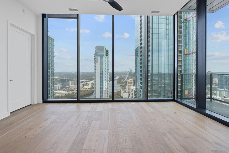 Room featuring floor to ceiling windows, a city view, light wood-style floors, and a ceiling fan