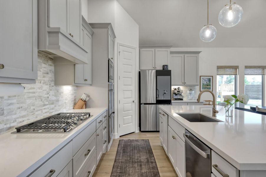 Quartz countertops, a stylish tile backsplash, and brass finishes set the tone for this refined, modern kitchen. Quartz countertops, a stylish tile backsplash, and brass finishes set the tone for this refined, modern kitchen.