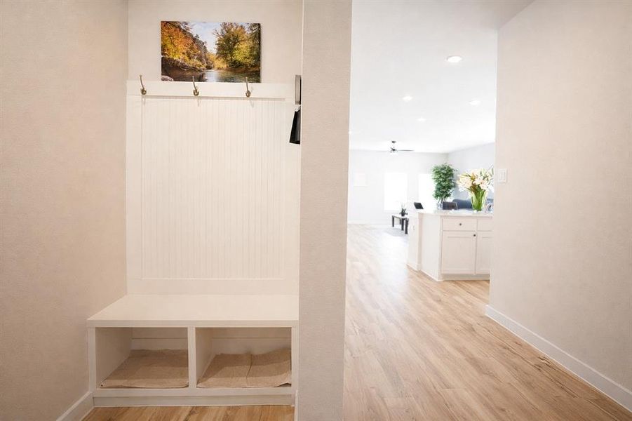 Built-in white storage bench with beadboard paneling and coat hooks