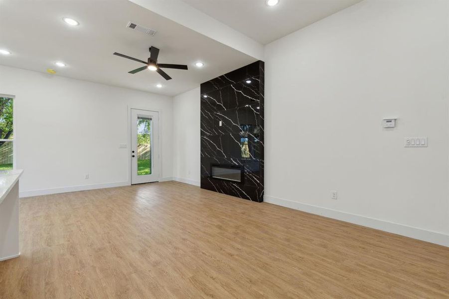 Unfurnished living room with light wood-type flooring, ceiling fan, and a fireplace