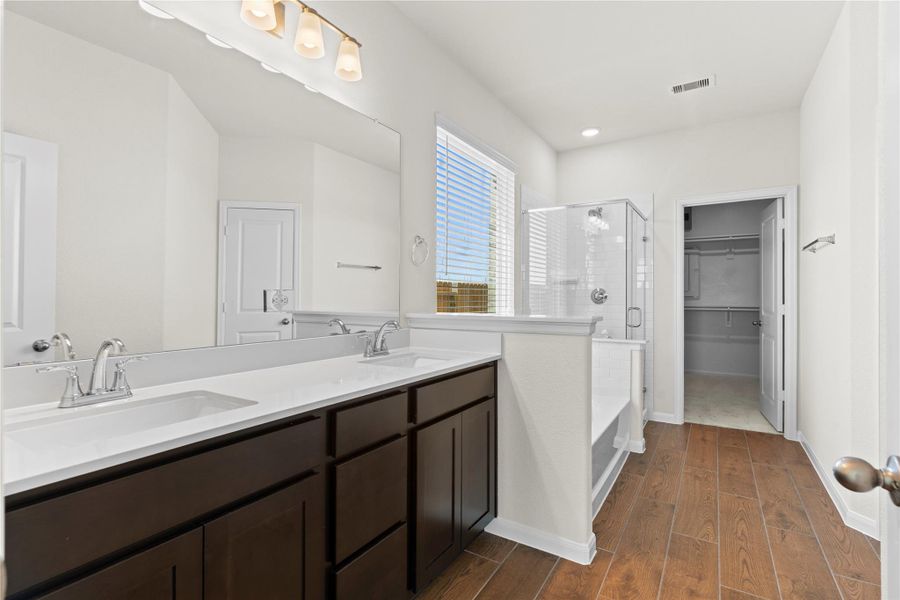 Spacious primary bathroom designed for comfort and functionality featuring dual sinks with beautiful cabinetry, plenty of counter space, and elegant finishes. The room also features durable tile flooring and a bright open layout that connects seamlessly to the walk in closet and shower area.