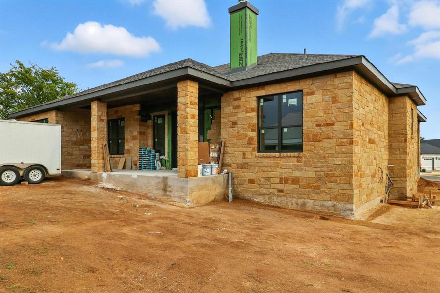 Rear view of property with stone siding and a patio area Rear view of property with stone siding and a patio area