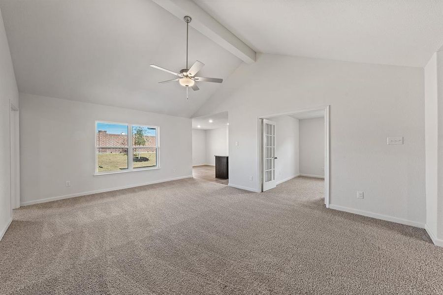 Unfurnished living room with a ceiling fan, baseboards, high vaulted ceiling, light carpet, and beamed ceiling