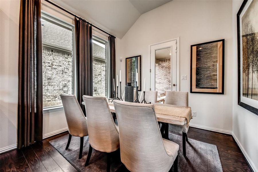 Dining area featuring vaulted ceiling and dark wood-style floors