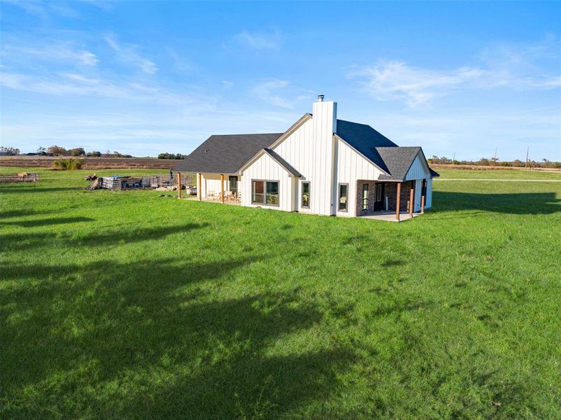 Back of house with a lawn and a rural view