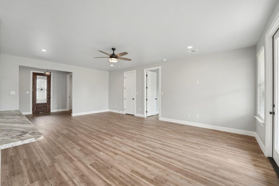 Unfurnished living room featuring light wood-style floors, visible vents, a wealth of natural light, and ceiling fan