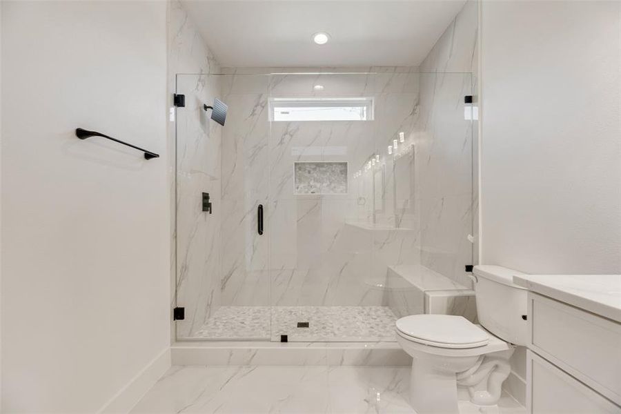 Full bathroom with a marble finish shower, vanity, and marble look tile flooring Full bathroom with a marble finish shower, vanity, and marble look tile flooring