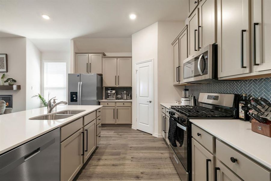 Kitchen featuring stainless steel appliances, gray cabinetry, light wood-style flooring, recessed lighting, and backsplash Kitchen featuring stainless steel appliances, gray cabinetry, light wood-style flooring, recessed lighting, and backsplash