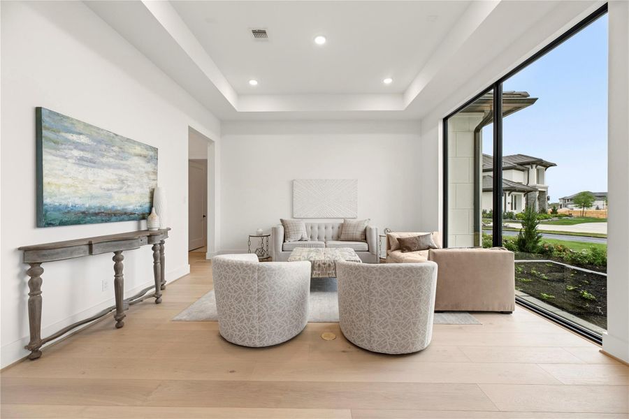 Bright sitting area with a tray ceiling and large windows offering plenty of natural light. Bright sitting area with a tray ceiling and large windows offering plenty of natural light.