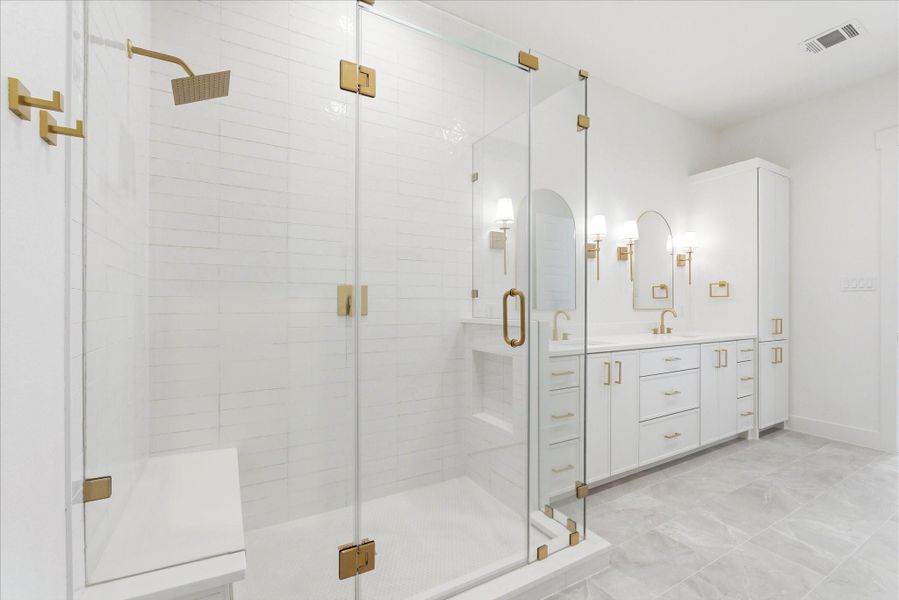 An ample walk-in shower is complete with a built-in bench and hidden soap niche for a clean, thoughtful finish.
