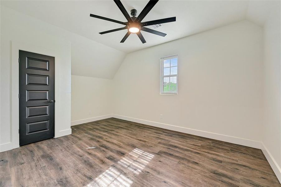 Bonus room featuring baseboards, ceiling fan, wood finished floors, and lofted ceiling