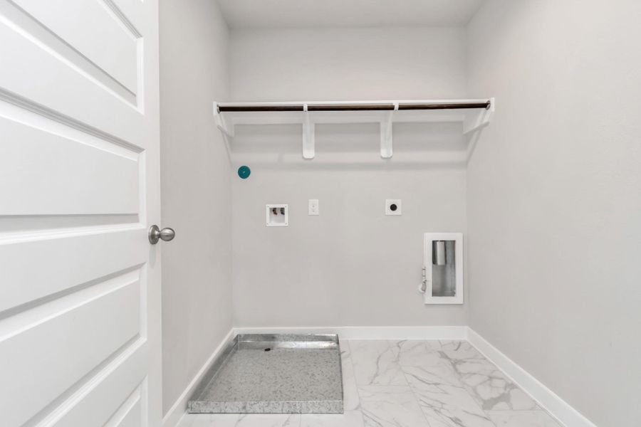 A perfect blend of functionality and comfort. Capture the essence of easy living with a first-floor laundry room, thoughtfully equipped with shelving for effortless organization. Both electric and gas connections available. Sample photo of completed home with similar floor plan. Actual colors and selections may vary.