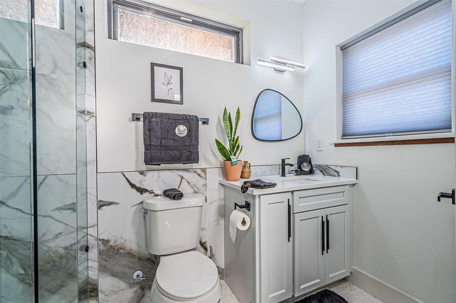 Bathroom featuring vanity and a marble finish shower