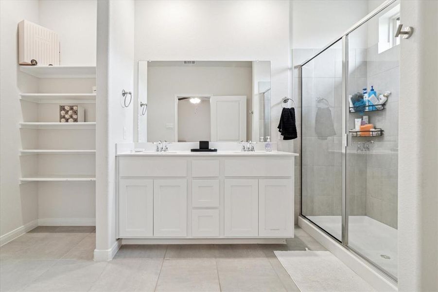 Full bath with double vanity, a shower stall, and light tile patterned flooring Full bath with double vanity, a shower stall, and light tile patterned flooring